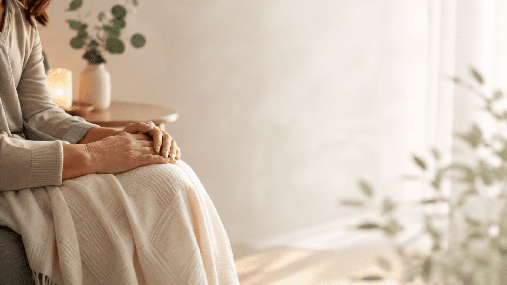 A person seated calmly at home, hands resting peacefully, evoking warmth and quiet support